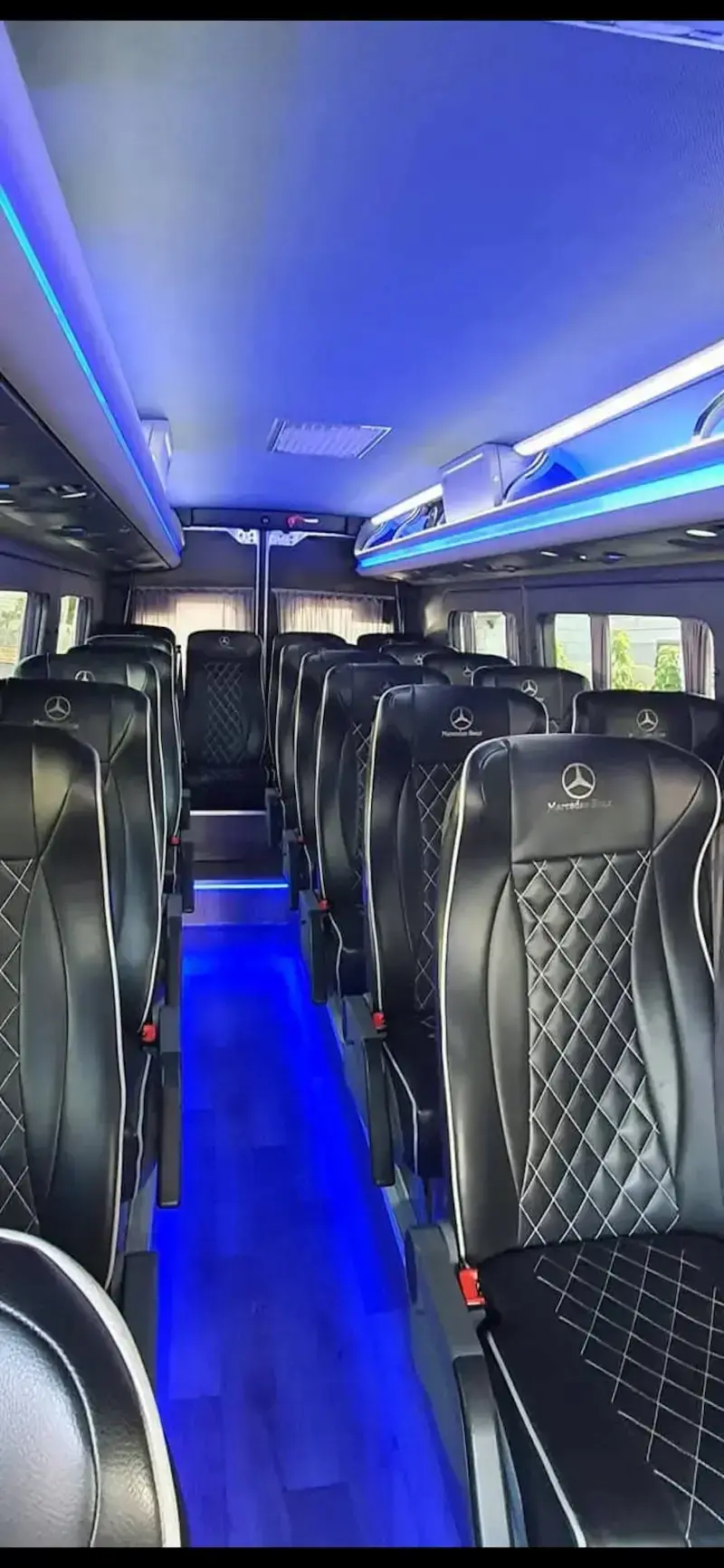 הסעות VIP בפריסה ארצית - פנים של מיניבוס VIP מפואר, הכולל מושבי עור שחורים, תפירת מעוינים ותאורת אווירה כחולה.
